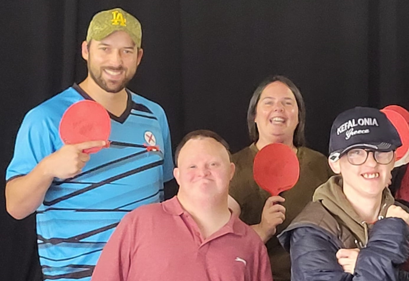 4 people holding table tennis bats smiling