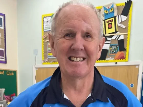 A man smiling standing in a primary school hall