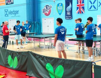 Coach talking to a group of young table tennis players