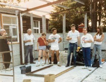A small group stands in a part built building
